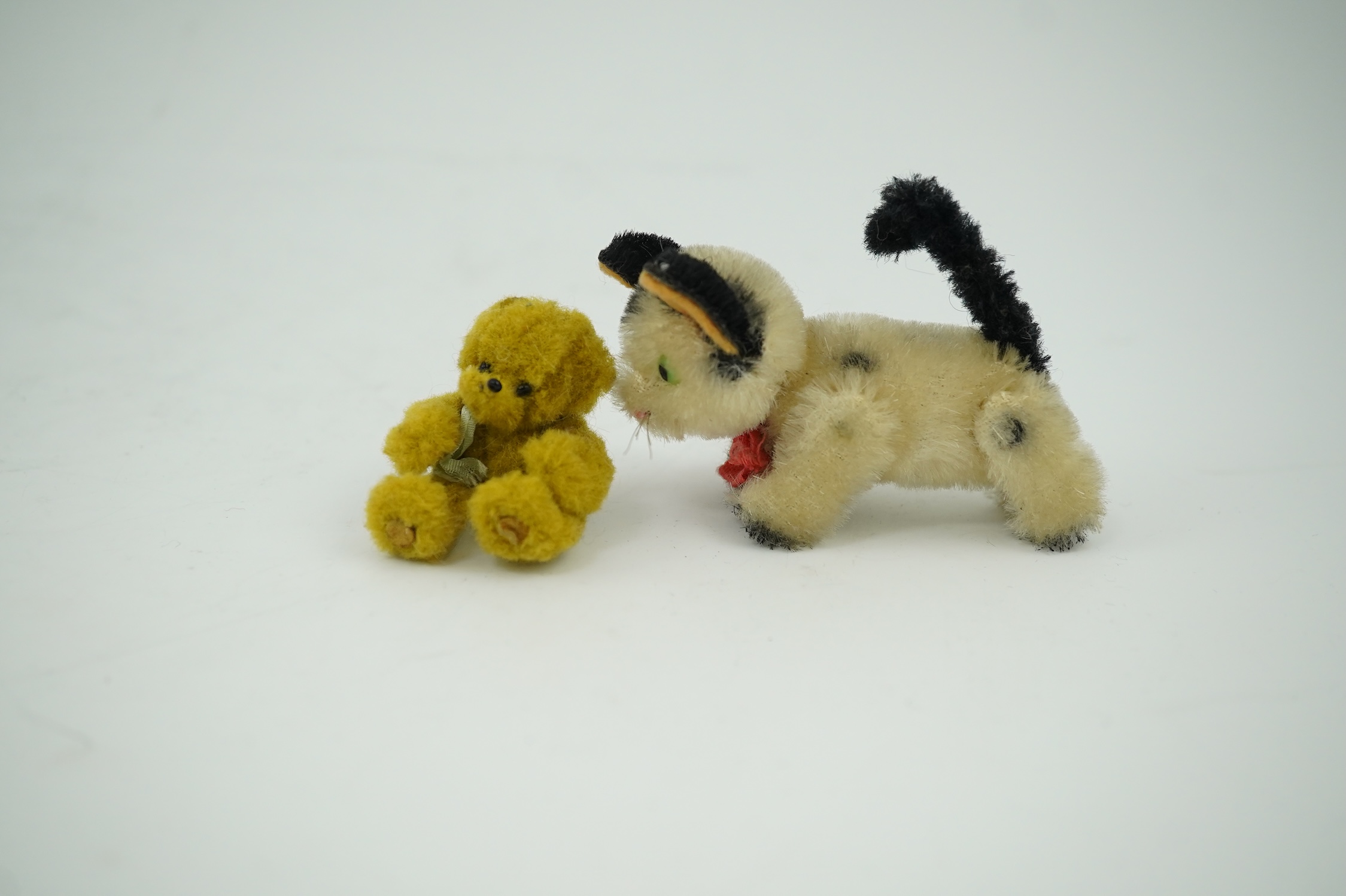 A small Schuco cat with revolving head and a tiny jointed teddy bear, largest 9cm in length. Condition - fair to good